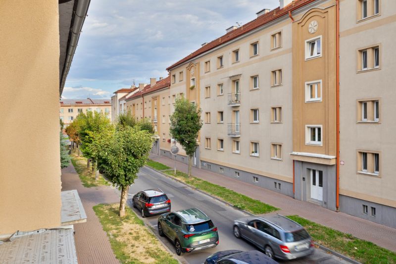 Ulice Študentská ve Zvolenu s bytovými domy a projíždějícími auty, vhodná pro garsonku.