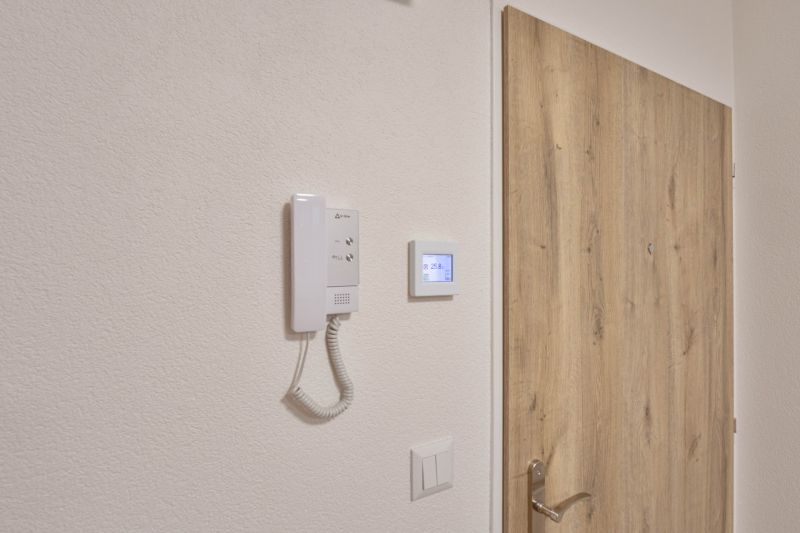 Dveře s dřevěným dekorem a interkom v garsonce.