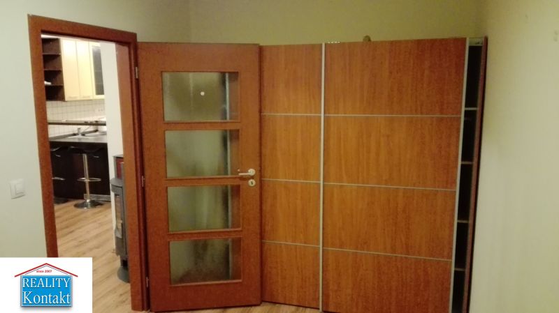 Otevírací dveře do kuchyně, podlaha s dřevěným dekorem, vchod vedoucí do 3pokojového bytu.