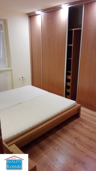 Ložnice s podlahou s dřevěným dekorem a vestavěnou skříní v 3-pokojovém bytě.