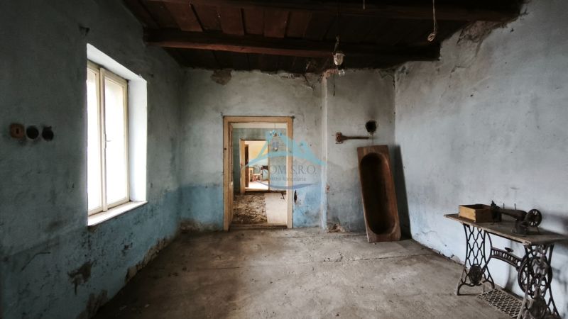 Pokoj v rodinném domě s modrými stěnami, starým šicím strojem a dřevěným korytem.