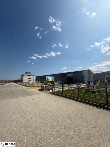Průmyslová budova v Hniezdnem s jasně modrou oblohou a příjezdovou cestou.