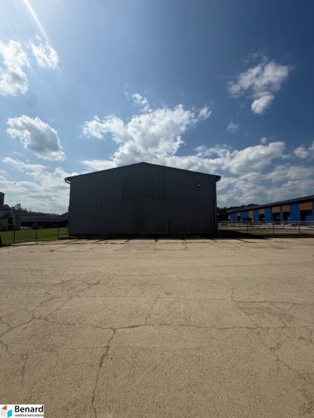 Budova v Hniezdnom s velkým zpevněným prostranstvím a modrou oblohou.