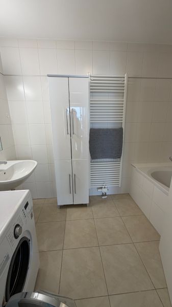 Koupelna ve 3-pokojovém bytě, s bílým nábytkem a pračkou.