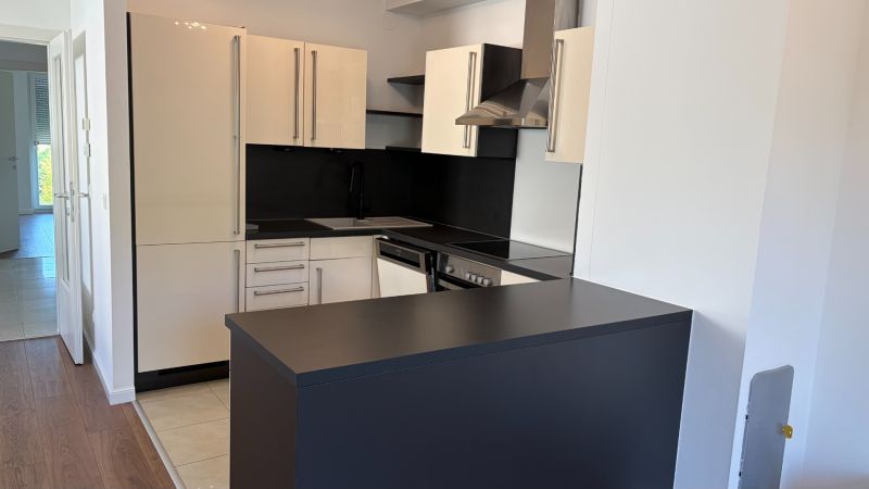 Kuchyně v 3-pokojovém bytě s elegantní černou deskou a světlými skříňkami.
