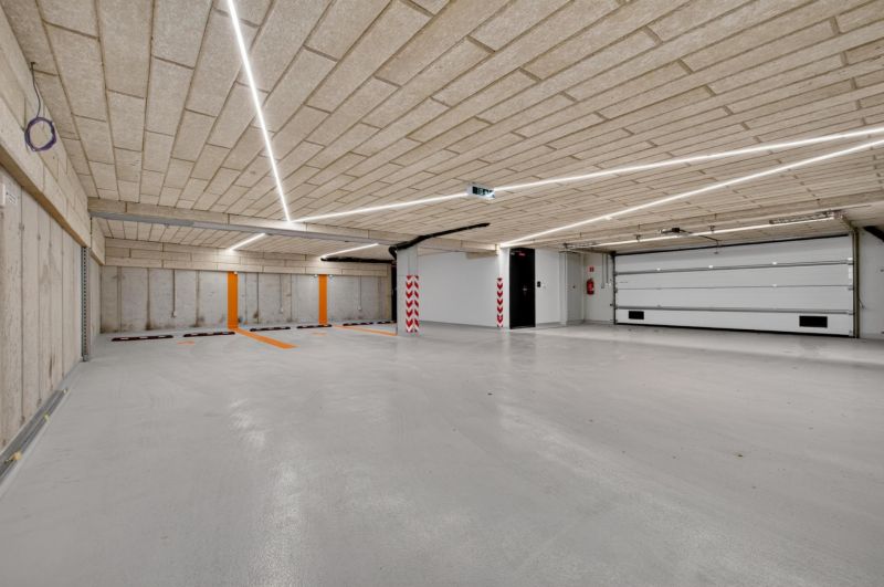 Parkovací garáž s betonovým stropem a podlahou, osvětlená lineárními svítidly.