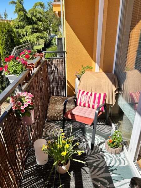 Balkon 3pokojového bytu s pohodlným sezením, květinami a výhledem na zeleň.
