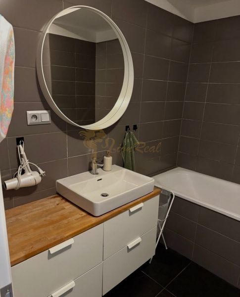 Koupelna v 2-pokojovém bytě s umyvadlem, zrcadlem a vanou, elegantní hnědé obklady.