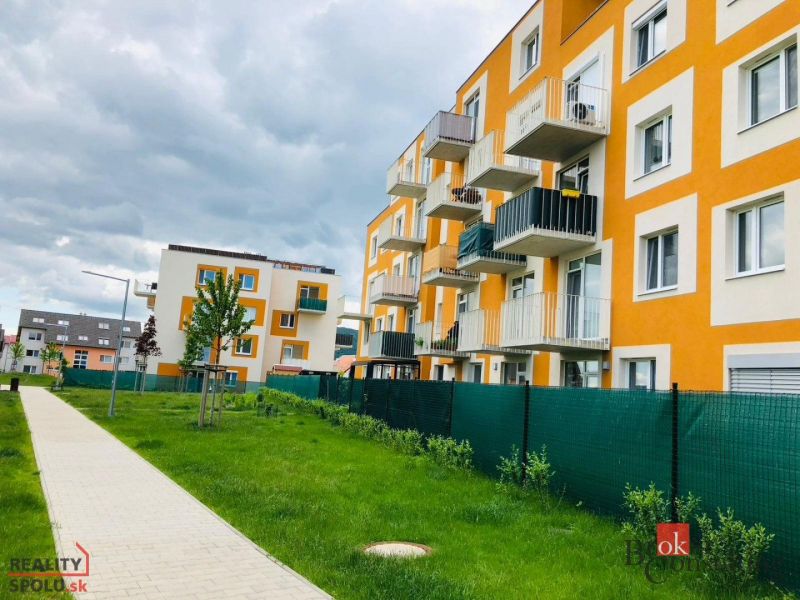 Bytový komplex na ulici Bystrická, Bratislava-Devínska Nová Ves, s chodníkem a travnatou plochou.