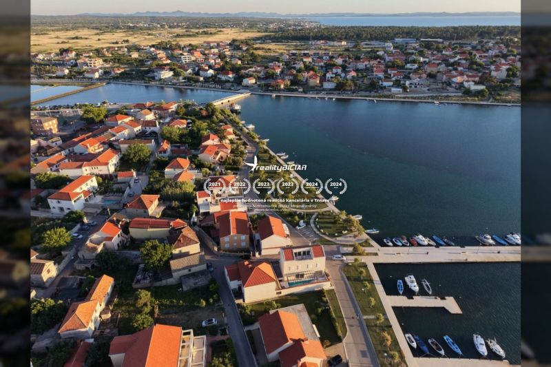 Letecký pohled na pobřežní oblast města Nin se střechami vil a přístavem.