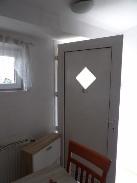 Vchodové dveře v 2-pokojovém bytě s dřevěným dekorem komody a židle.