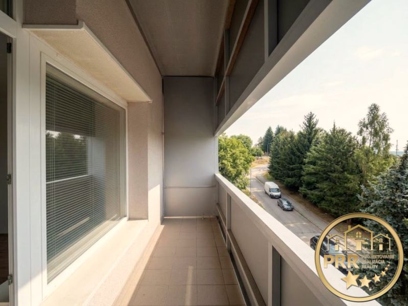 Balkon 2-pokojového bytu v Bánovcích nad Bebravou s výhledem na silnici a stromy.