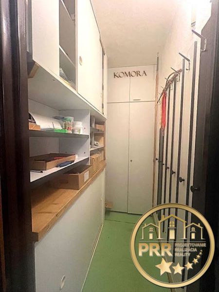 Úložný prostor v 2-pokojovém bytě s poličkami a boxy, zelené podlahy.