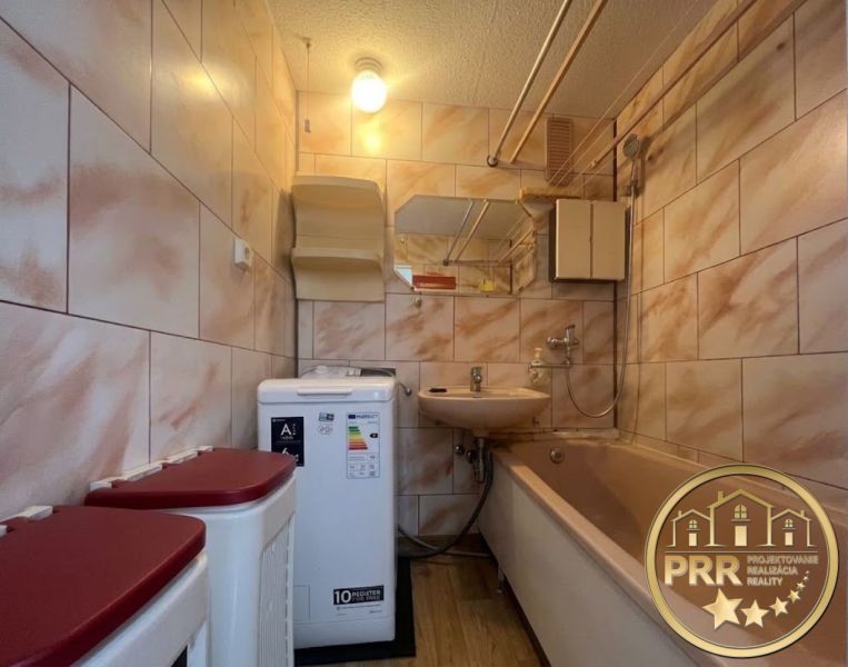 Koupelna v 2-pokojovém bytě s vanou, umyvadlem, pračkou a dlaždicemi.