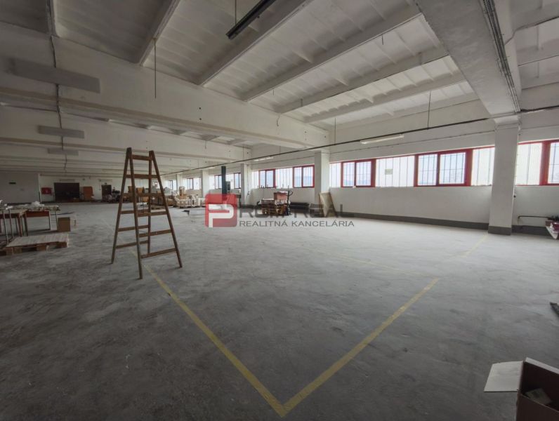 Prostor s betonovou podlahou a pracovním obsahem ve výrobních prostorách.