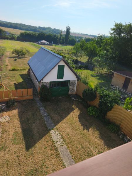 Zahrada a stavba u rodinného domu v Jelenci, obklopené poli a stromy.