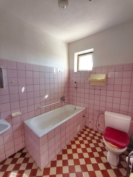 Koupelna s růžovými dlaždicemi a bílou vanou v rodinném domě.