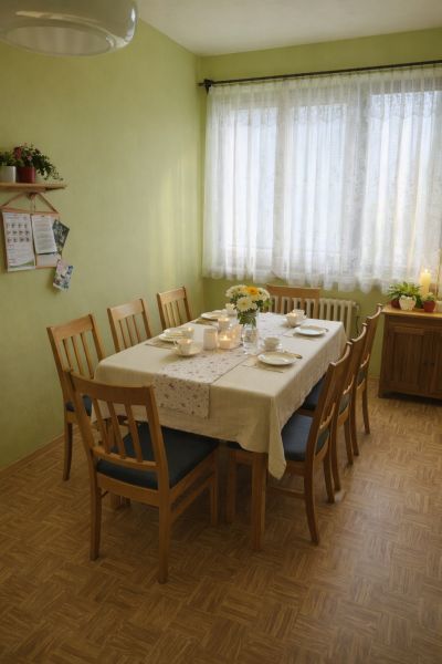 Jídelna v rodinném domě s prostřeným stolem a podlahou s dřevěným dekorem.