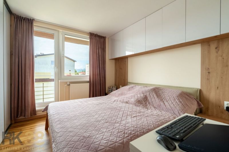 Ložnice s růžovou přikrývkou ve 3-pokojovém bytě, vybavená podlahou s dřevěným dekorem.