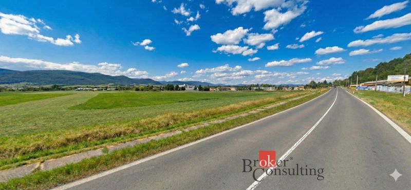Hliník nad Hronom, Pozemky - komerční, zelené louky u cesty obklopené kopci a budovami.
