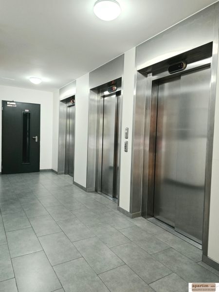 Chodba se čtyřmi kovovými výtahy a šedou dlažbou ve 4-pokojovém bytě.