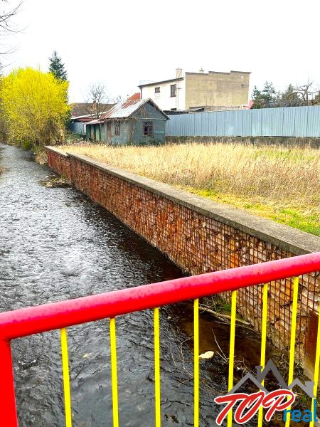 Obrázek z Jarkové ulice, Košice - městská část Šaca, s říčkou a přilehlými pozemky.
