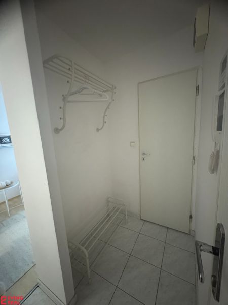 Předsíň s věšákem a botníkem v 1-pokojovém bytě s dlažbou na podlaze.
