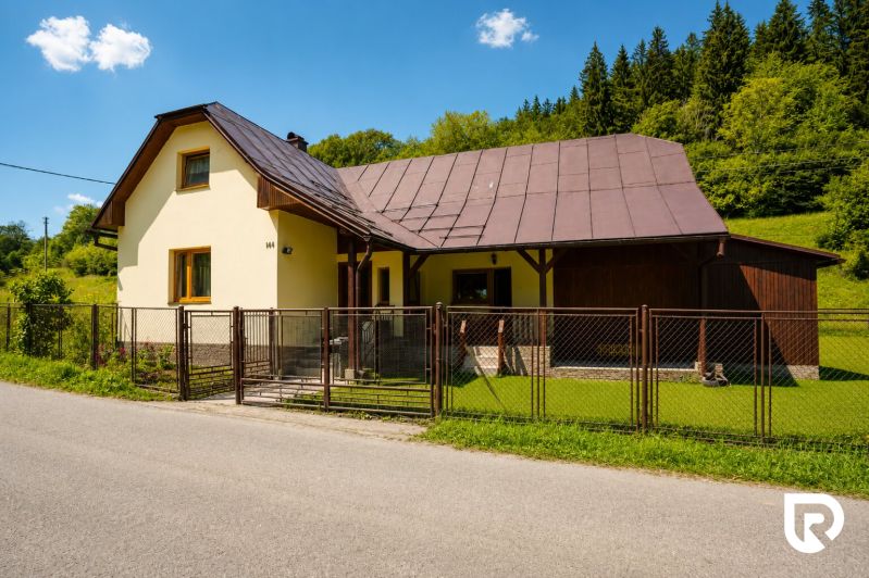 Chata na ulici Černé v Makově s okrasným trávníkem a dřevěným plotem.