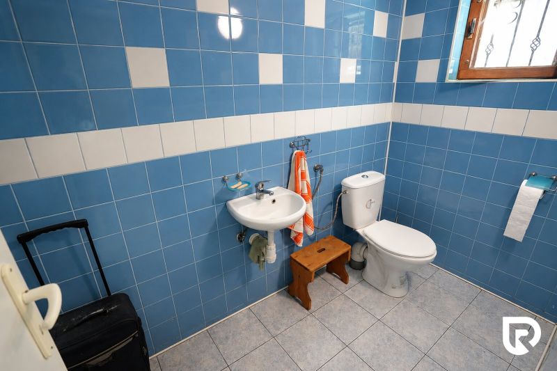 Koupelna v rodinném domě s modrými kachličkami, umyvadlem a WC.