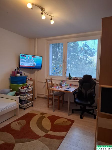 Dětský pokoj s postelí, stolem a podlahou s dřevěným dekorem ve 3-pokojovém bytě.