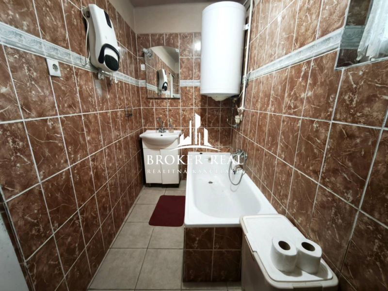 Koupelna v rodinném domě s hnědými dlaždicemi a vanou.