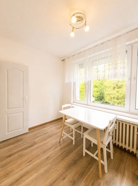 Jídelní kout s bílým stolem a židlemi, podlaha s dřevěným dekorem, 3-pokojový byt.