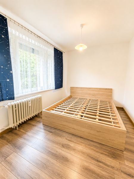 Ložnice s podlahou s dřevěným dekorem a postelí ve 3-pokojovém bytě.