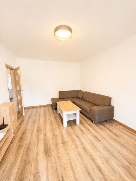 Obývací pokoj s hnědou sedačkou a stolkem na podlaze s dřevěným dekorem ve 3-pokojovém bytě.