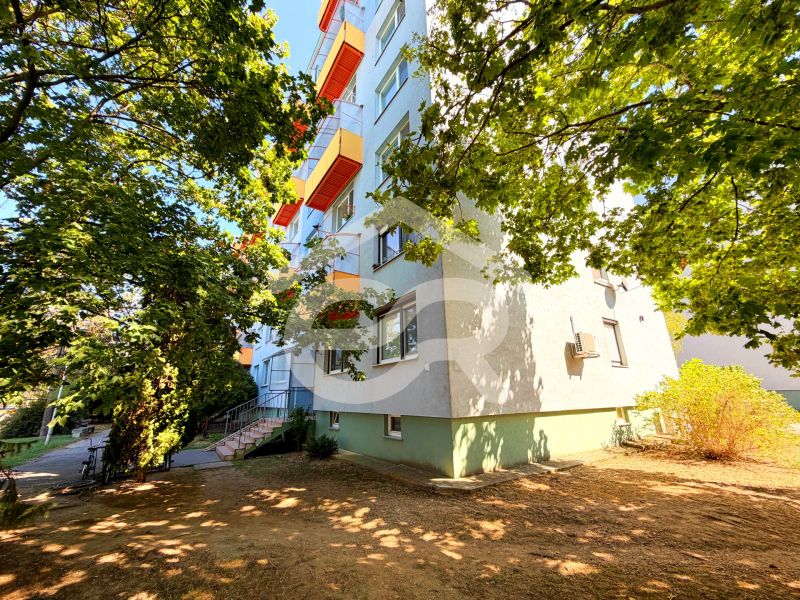 Bytovka s barevnými balkóny na ulici Lúky ve Vráblech, obklopená stromy.