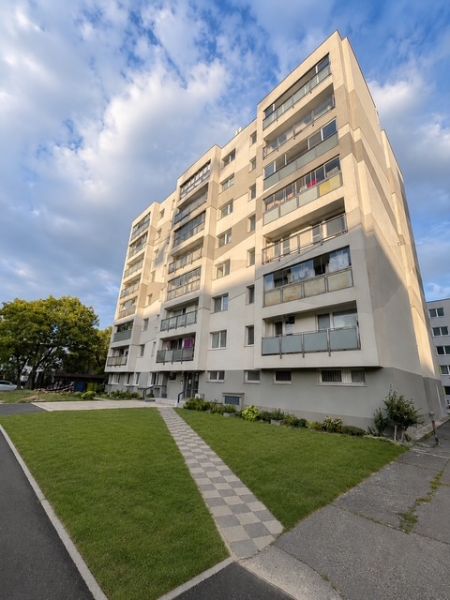 Bytový dům na Nobelově ulici v Bratislavě s upraveným trávníkem před budovou.