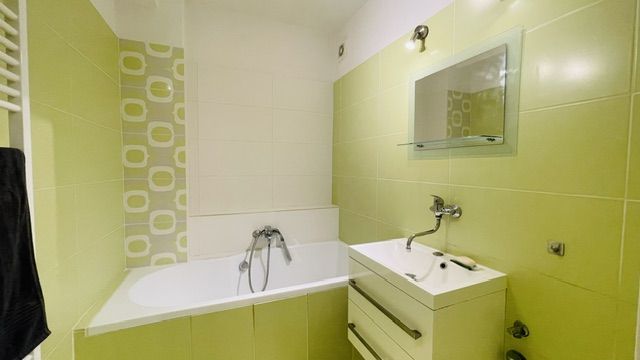 Zeleno-bílá koupelna s vanou a umyvadlem ve 3-pokojovém bytě.