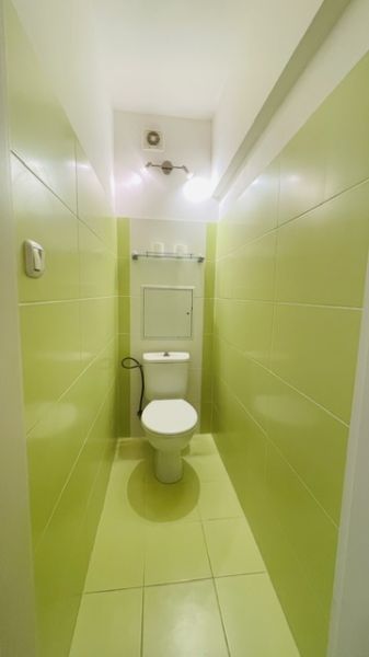 Úzká koupelna se světle zelenými dlaždicemi a toaletou ve 3pokojovém bytě.