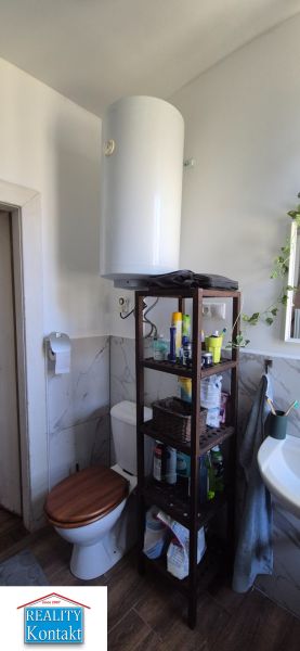 Koupelna v 2-pokojovém bytě obsahuje WC, policový regál a umyvadlo.