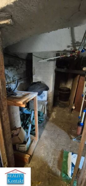 Suterénní prostor v 2pokojovém bytě s úložnými policemi a potrubím.