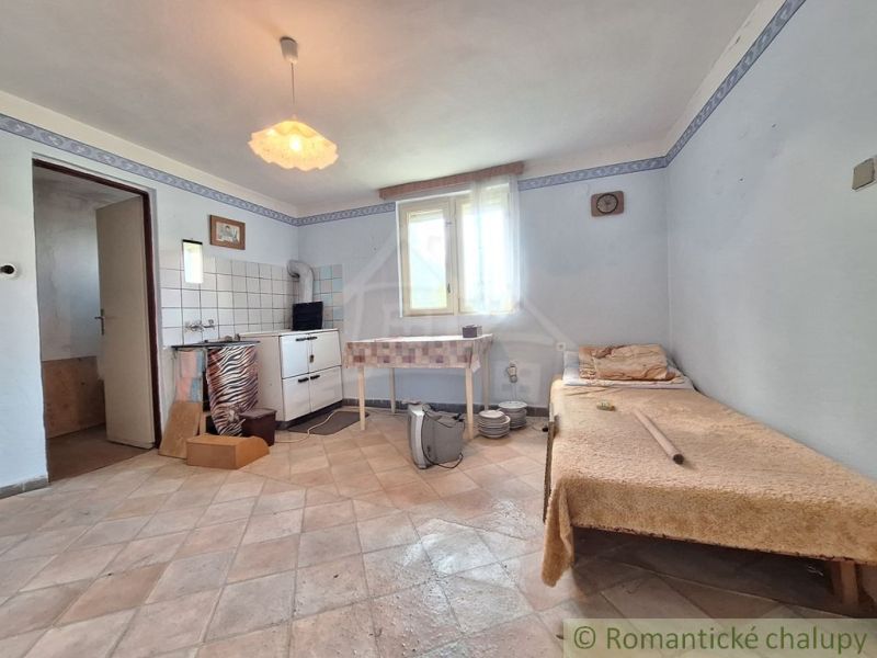 V rodinném domě je jednoduchý pokoj s kuchyňským koutem a křeslem.