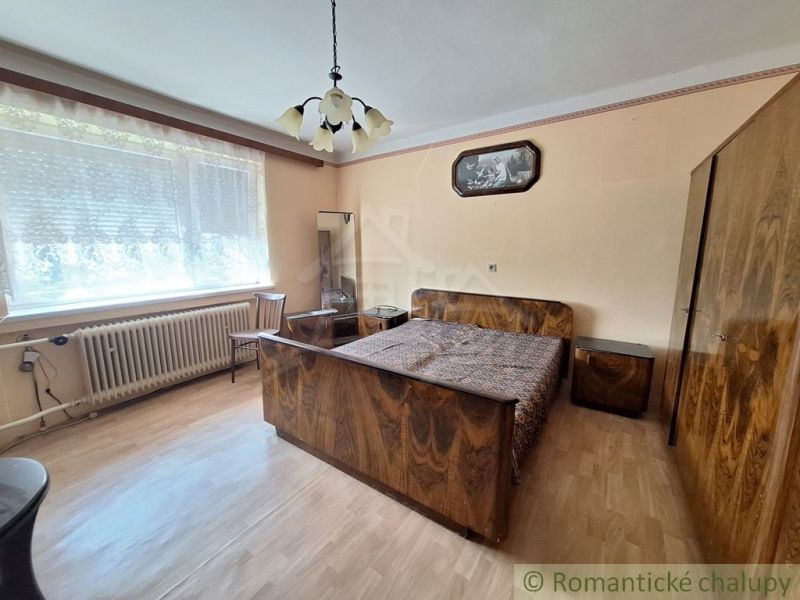 Ložnice v rodinném domě s podlahou s dřevěným dekorem a stylovým nábytkem.
