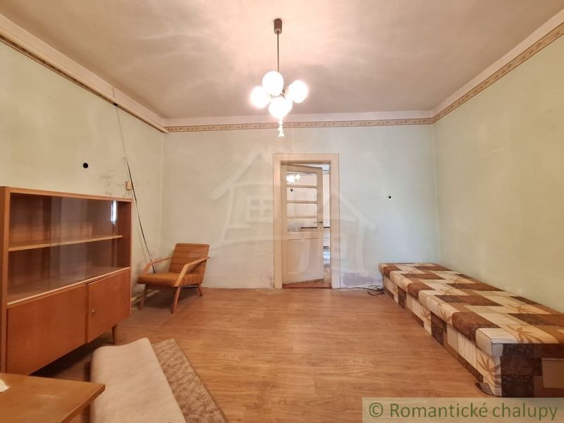 Obývací pokoj v rodinném domě s dřevěným dekorem a retro nábytkem.