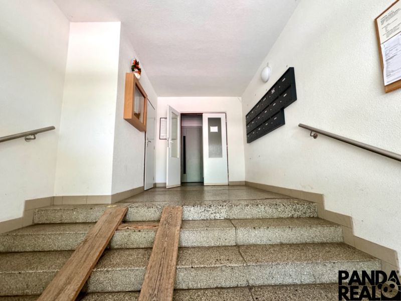 Vstupní hala v bytovém domě s poštovními schránkami a výtahem.