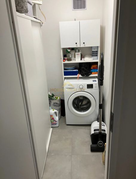 Prádelna s pračkou a úložnými skříňkami v 3-pokojovém bytě.