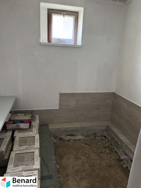 Interiér rodinného domu s oknem a broušenou podlahou, příprava na dlažbu.