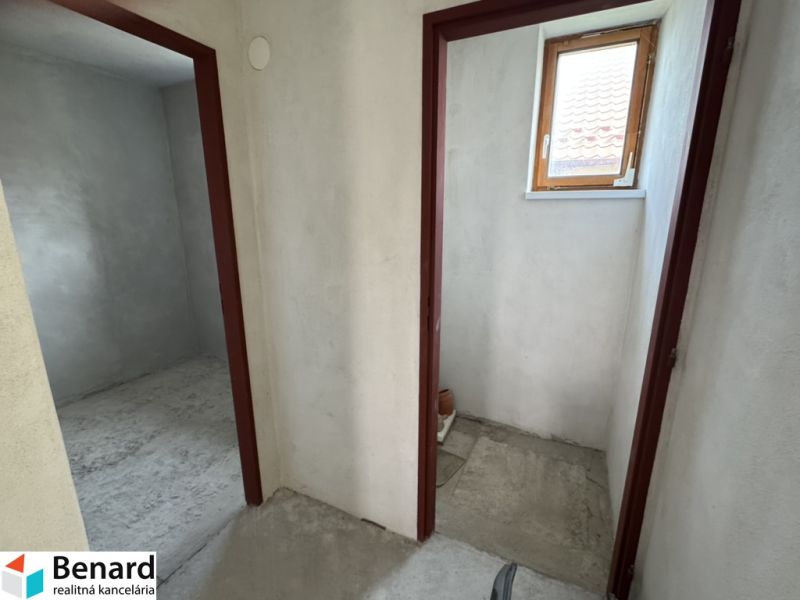 V rodinném domě se nacházejí dvě místnosti s betonovou podlahou a malým oknem.
