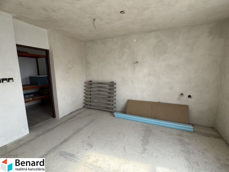 Interiér rodinného domu s nedokončenými stěnami a podlahou, s materiály na podlaze.