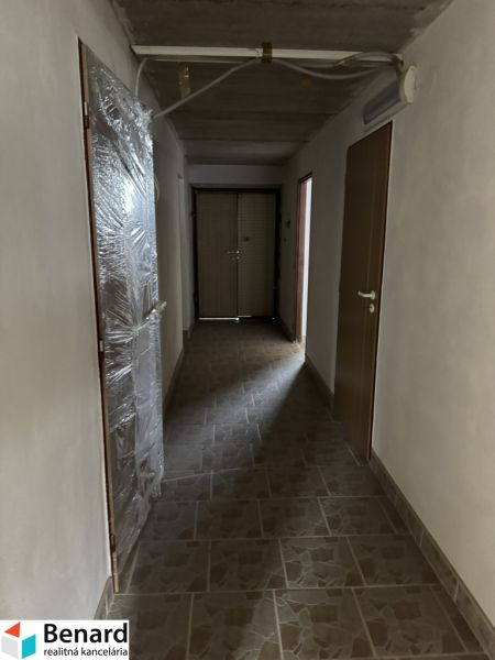 Chodba v rodinném domě, s béžovou dlažbou na podlaze a plastovými dveřmi.