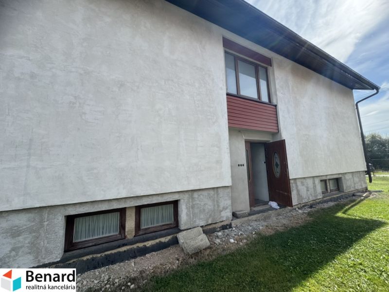 Rodinný dům v Plavnici se světlou omítkou a dřevěnými okny v přízemí.